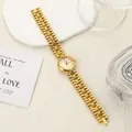 Close-up of elegant gold chain watch with vintage round dial on a white textured surface. - Gold