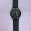 Detailopname van de groene wijzerplaat met denimtextuur en bronzen kast van een kwartshorloge - Groen