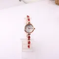 Close-up detail of a rose gold women's quartz watch featuring a red rhinestone bracelet - Red