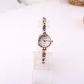 Elegant rose gold quartz bracelet watch featuring blue crystals displayed on clear stand - Blue