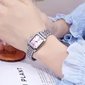 Detailansicht einer silbernen quadratischen Quarzuhr mit rosa Zifferblatt am Handgelenk eines Models - Silberrosa