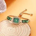 Close-up of mini square rose gold watch with green dial and sparkling crystal bezel. - Green