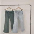 Dettaglio di jeans svasati blu chiaro e verde retrò su un appendiabiti in metallo - Taglia L / Pantaloni e gonne / Azzurro