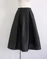 Detailed view of a black silk-wool blend pleated A-line midi skirt on a mannequin - S / Bottoms / Black