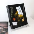 Vista detallada de un marco de caja de sombra 3D negro con flores y tickets retro - Negro