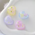 Close-up of four embossed heart-shaped beads with floral patterns in pastel colors. - 1 Piece (27x21.3mm) / Pink