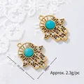 Detailed view of Hamsa hand gold-plated charms with turquoise stone on white lace background - Zirconia Hamsa Hand