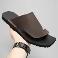 Mano sosteniendo sandalias romanas de hombre con lazo en marrón y negro para la playa - 40 / Estilo Marrón (F611) / Marrón