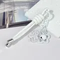 Close-up detail of white leather cord keychain with signature knot design and bell charm - Peruvian Knot / White