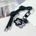 Macro shot of a black leather DIY bag charm featuring bell and acrylic star pendants - Double Knot / Black