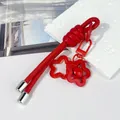 Primer plano del llavero de cuero rojo con cascabel de flores y dijes de estrellas - Nudo peruano / Rojo