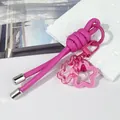 Primer plano de un llavero creativo de cordón de cuero rosa con colgantes de flores - Nudo peruano / Rosa rojo