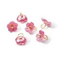 Close-up of iridescent pink pearlescent flower pendants with golden jump rings - Rose Red