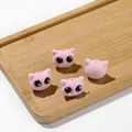 Gros plan de perles de chat floquées roses avec de grands yeux noirs sur un plateau en bois - Rose