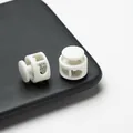 Detailed view of white double-hole plastic spring cord locks for drawstring adjustment - Double Hole Spring Adjustment Buckle / 10 Pieces Pack / Solid Nylon White