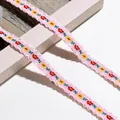 Detailansicht der rosa geblümten Stickspitze mit zarten Wellenkanten und Blumen - 1m / Rosa Rot Gelb