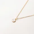 Minimalistische goldene Halskette mit einem runden Anhänger aus weißem Emaille-U - Buchstabe U