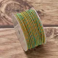 Close-up detail of 2.5mm gold and teal braided jewelry cord on a clear plastic spool - Yellow Lake Blue