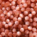 Detailed macro view of shimmering peach cat-eye resin beads with fine pink glitter powder - 10 Pieces/Pack (10mm/Aperture 1.8mm) / Red Brown