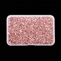 Detailed view of irregular rose gold metallic glass stones in a transparent storage box. - Pink