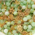 Nahaufnahme von grünen Kunstperlen und goldenen Metallanhängern für DIY-Schmuck. - 30g Pro Packung / Grün + Gold Mix