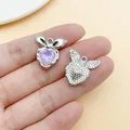 Hand hält silbernen Herzanhänger mit lila Zirkonia und Schleife für die DIY-Schmuckherstellung - Irisierendes Schleifenherz (28425)