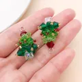 Macro detail of handmade beaded crystal Christmas tree pendants held in a hand for scale - Green Crystal Beaded Christmas Tree (28619)