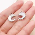 Dijes de delfín plateados para la creación de joyas DIY, mostrados en una mano humana. - Delfín Iridiscente (28149) / 1 Pieza / Blanco