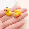 Close-up of two cute yellow resin duck charms with silver metal rings on a hand - Yellow Resin Small Duck (17217) / 1 Piece (17x19mm) / Yellow