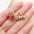 Hand holding gold-plated cherry pendant charms with faceted red rhinestone crystals - Bow Rhinestone Style (23398) / 1 Piece (16x14x6mm) / KC Gold Red Bow Rhinestone Cherry