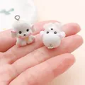 Two cute white cartoon dog resin charms held on a human palm for DIY jewelry crafts - Bichon with Bell (27728)