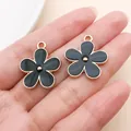 Close-up of two black enamel flower charms for DIY jewelry making on a palm - Double-Sided Floral (27583)