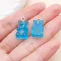 Detail view of blue translucent resin gummy bear charms on a hand for scale - Bear Candy (12568) / 1 Piece/Pack (10x20mm) / Lake Blue