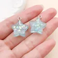 Pair of cute ice blue resin star charms with glitter and small stars, shown in hand - Transparent Glitter Sequin Star (24321)