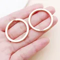 Close-up of rose gold flat metal split key rings held in hand for size comparison - 30x30mm / Rose Gold