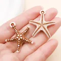 Primer plano de dos colgantes de estrella de mar de acrílico en marrón y blanco para joyería DIY - Estrella de mar (27393) / 1 Pieza (31.5x29mm) / Marrón