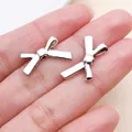 Primer plano de dos colgantes de lazo hueco en tono plateado para joyería de bricolaje - Cuentas de lazos de plata antigua (orificio recto)
