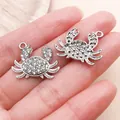 Detailed view of two silver crab charms with rhinestones held in a hand for DIY jewelry. - Rhinestone Ocean Crab Pendant (27122) / 1 Piece (18x22mm) / Silver