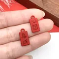 Detalle de pequeños dijes rectangulares rojos con caracteres chinos en relieve - Colgante con Texto de Éxito de Doble Cara Rojo (21573) / 1 Pieza (16x8mm)
