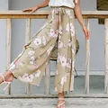Detail view showing floral print fabric and side slit of wide-leg trousers on a model. - S / Bottoms / Yellow