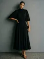 Elegante vrouw in een zwarte midi-jurk met hoge nek en pofmouwen in een studio-omgeving - S / Dresses / Zwart