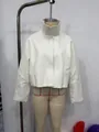 Détail d'une veste courte blanche en similicuir à col montant rétro et manches évasées - S / Hauts / Blanc