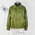Dettaglio di un'elegante giacca in ecopelle verde con colletto a rever e orlo elastico - Verde