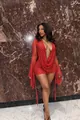 Detail of a sexy red polka-dot mini dress with a deep V-neck and flared sleeves on a model. - S / Dresses / Red