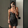 A stylish mirror selfie detailing a black sleeveless mini dress with white polka dots - Black