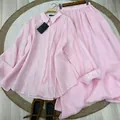 Detailed view of pink linen long-sleeve shirt and matching maxi skirt set on a woven rug - Pink