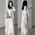 Elegant white long-sleeved satin maxi dress with ruffled detailing and cinched waist. - White