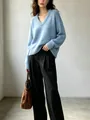 Donna che indossa un maglione di maglia azzurro oversize con scollo a V e pantaloni neri - XS / Top / Celeste