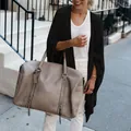 Detail view of a black knit cardigan with an irregular hem styled with a beige bag - Black