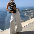 Chic white high-waisted wide-leg trousers for women shown in a coastal vacation setting. - S / Bottoms / White